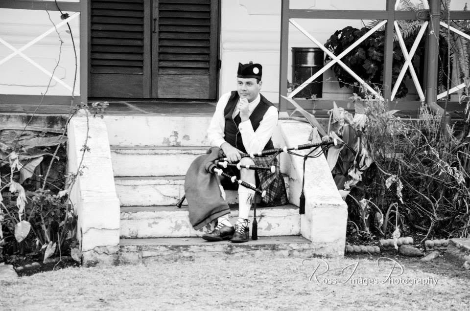 Piper Paul seated with bagpipes in Scottish attire
