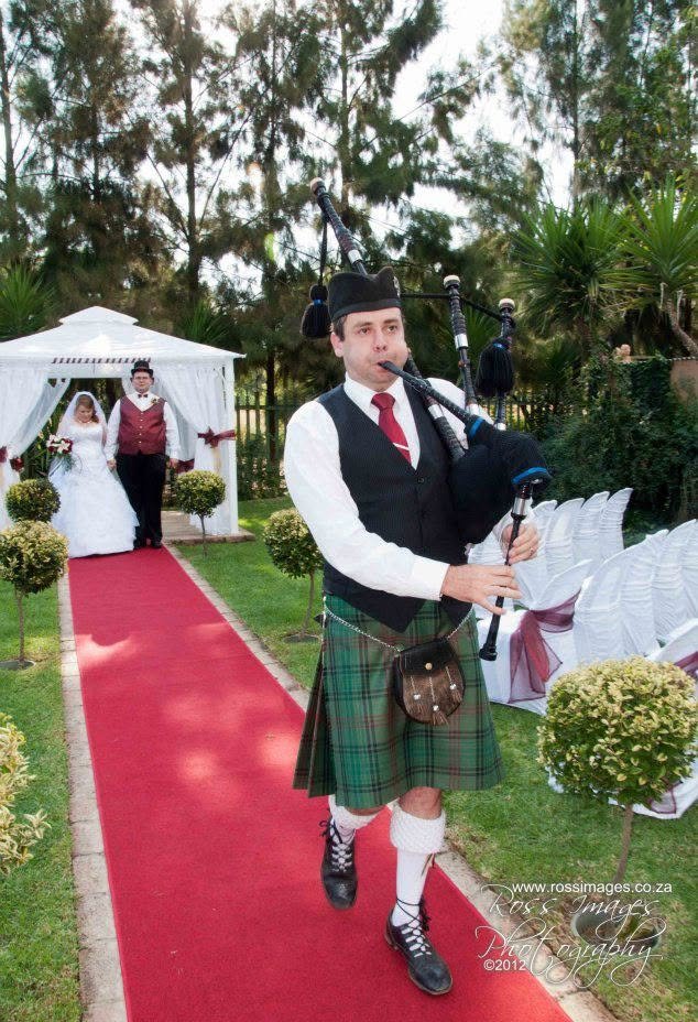 Piper Paul playing bagpipes at a wedding aisle